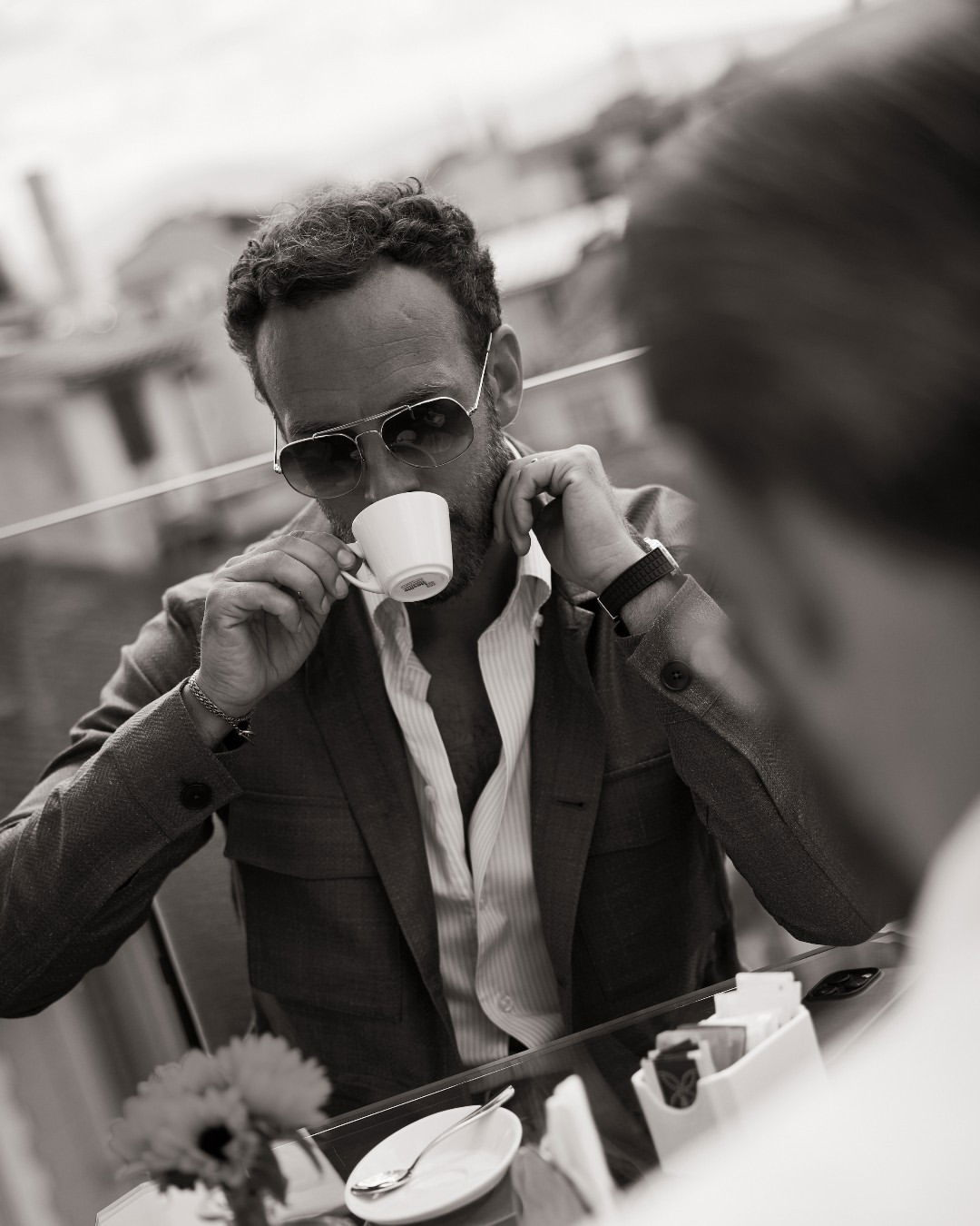 Photo shared by Eton Shirts Official on July 25, 2024 tagging @richardaldur, and @andreasweinas. May be a black-and-white image of 1 person, smoking, eyewear, wrist watch, dinner jacket, blazer, suit, tea and text.